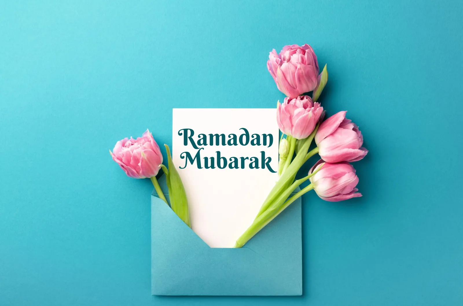 Ramadan Mubarak written on a white paper which is presented with pink tulips.