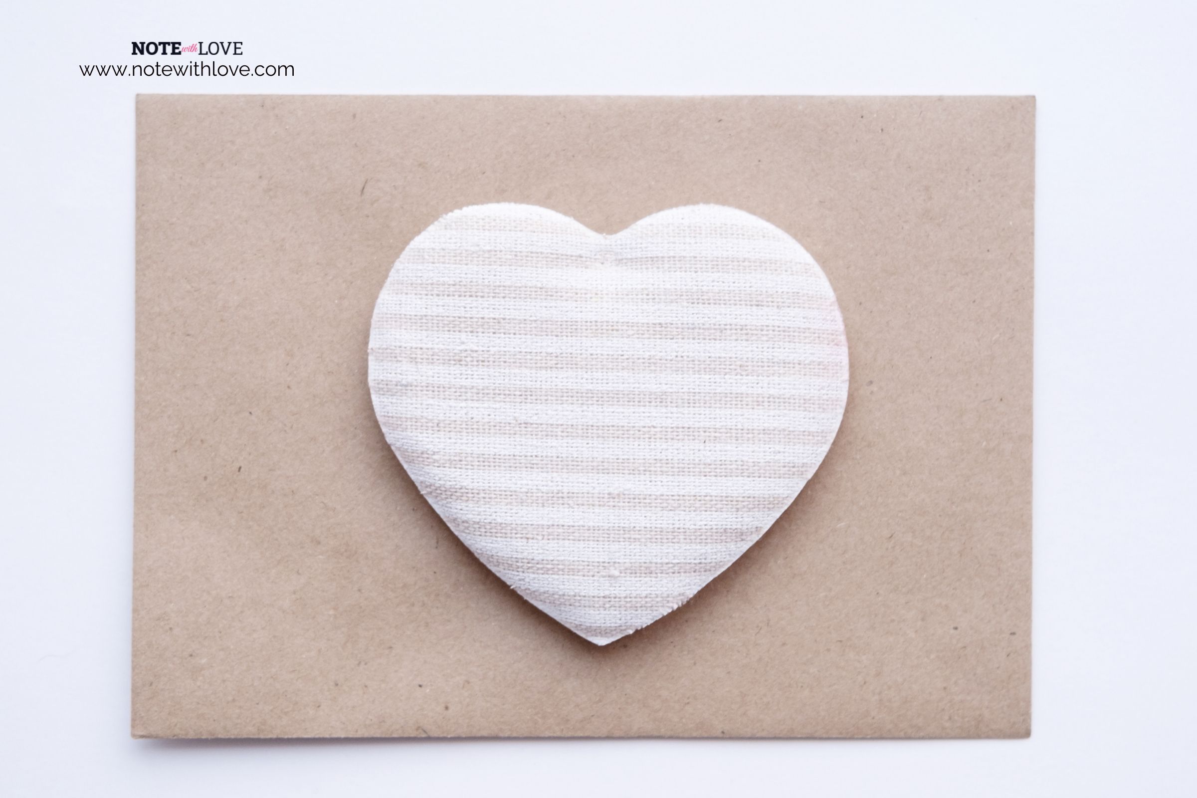 A white and light pink striped heart shaped decor kept on a brown envelope.